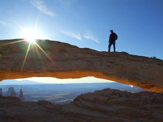Man standing on an arch in the desert